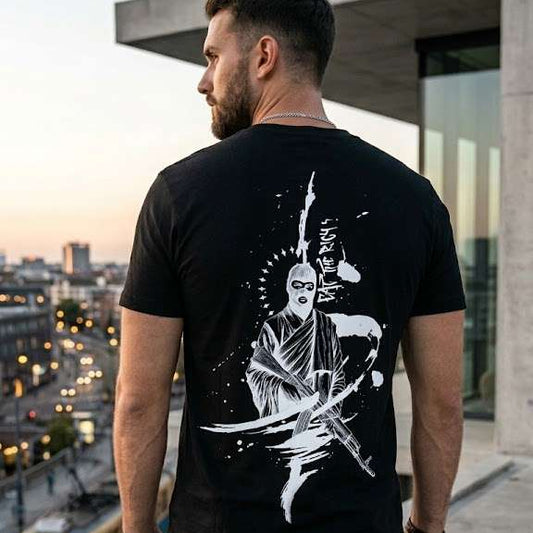 Mann von hinten in schwarzem T‑Shirt mit weißer Rückengrafik eat the rich vor urbaner Kulisse.