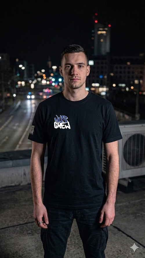 Mann trägt schwarzes T-Shirt mit Aufdruck 'eat the rich' vor nächtlicher Stadtkulisse.