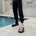 Stylish Black Slide Sandals with Graphic Design worn by a person near a pool.