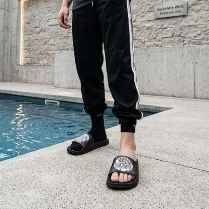 Stylish Black Slide Sandals with Graphic Design worn by a person near a pool.